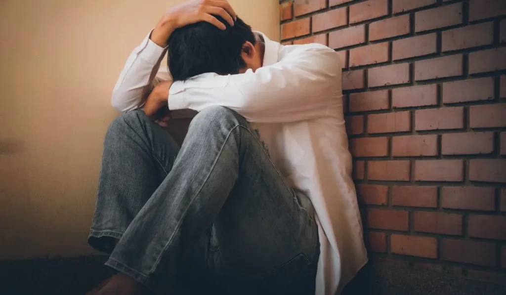 fcdae143-7aa8-44d5-9e63-38090f6a7af3webp - Lynk Diagnostics man sitting against the wall depressed
