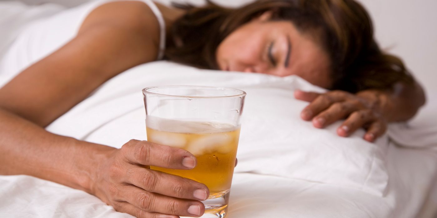 woman sleeping with alcohol in hands