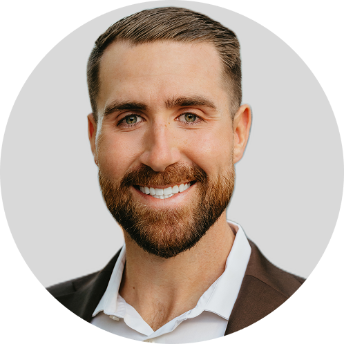 James - Lynk Diagnostics - Lynk Diagnostics Professional headshot of a smiling man with brown hair and a beard, in a white shirt and brown blazer.